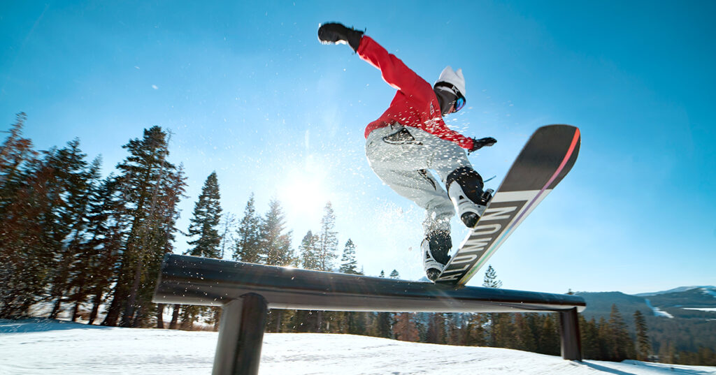 A snowboarder in the terrain park on a rail.