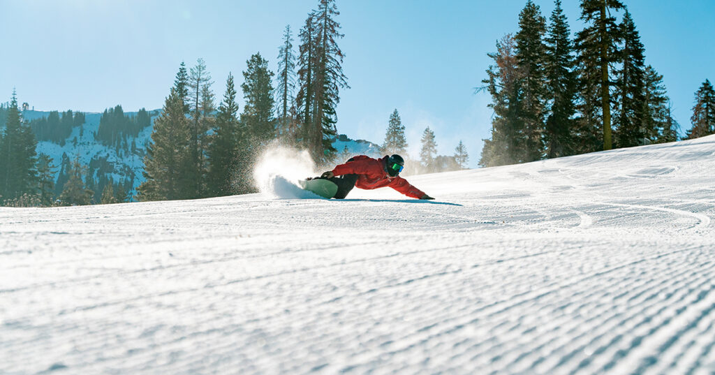 Snowboarder carving a turn on fresh corduroy
