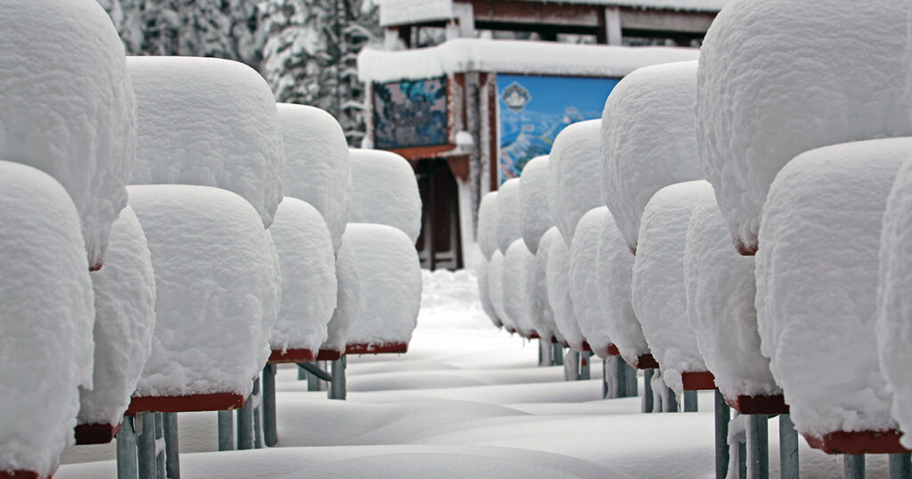 Picnic tables covered in snow.