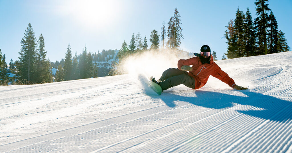 Snowboarder carving a turn on fresh corduroy.